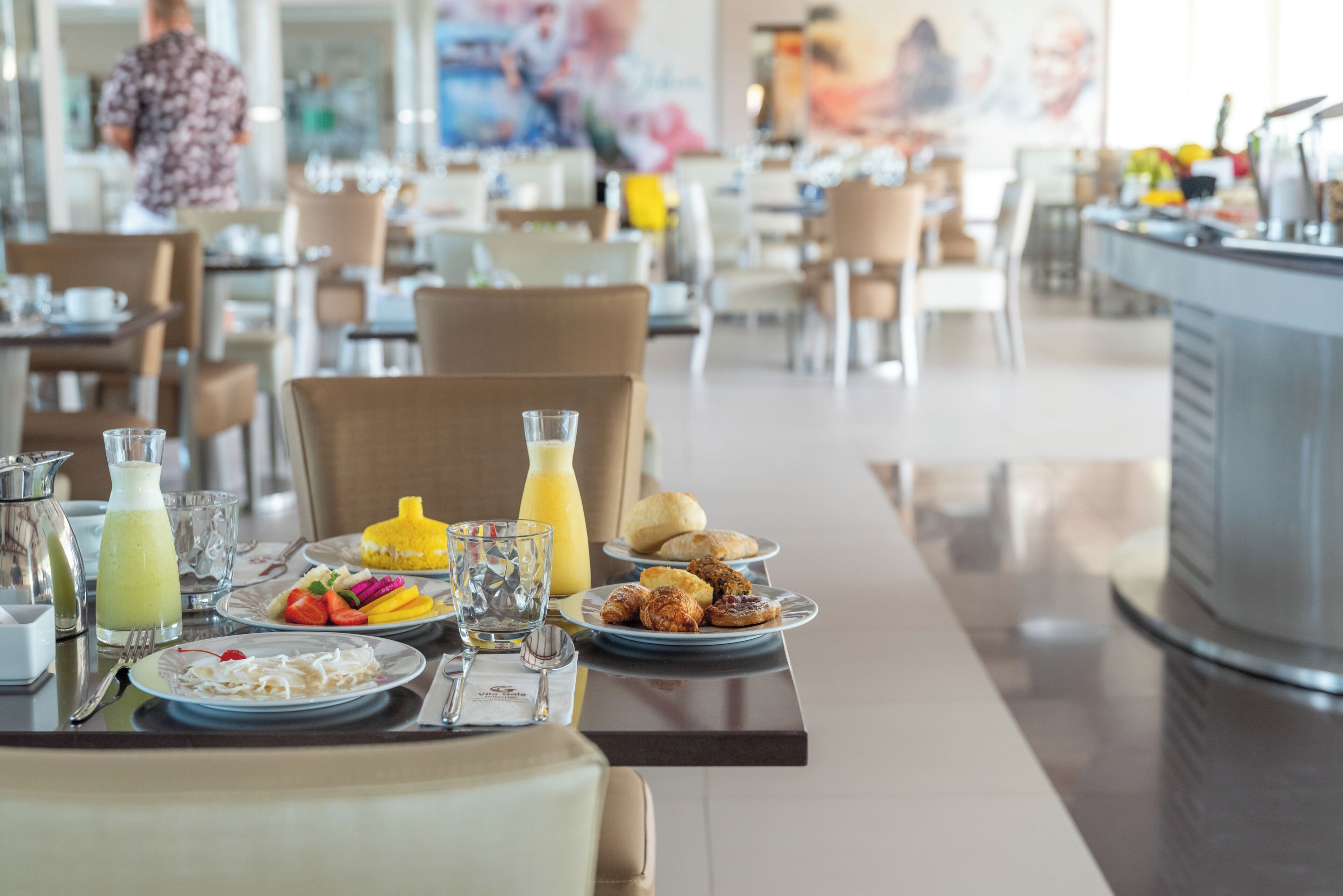 A breakfast table with plates of food, a pitcher, and a glass of juice.