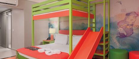 A child-friendly room with a bunk bed, a slide, and a mermaid mural.