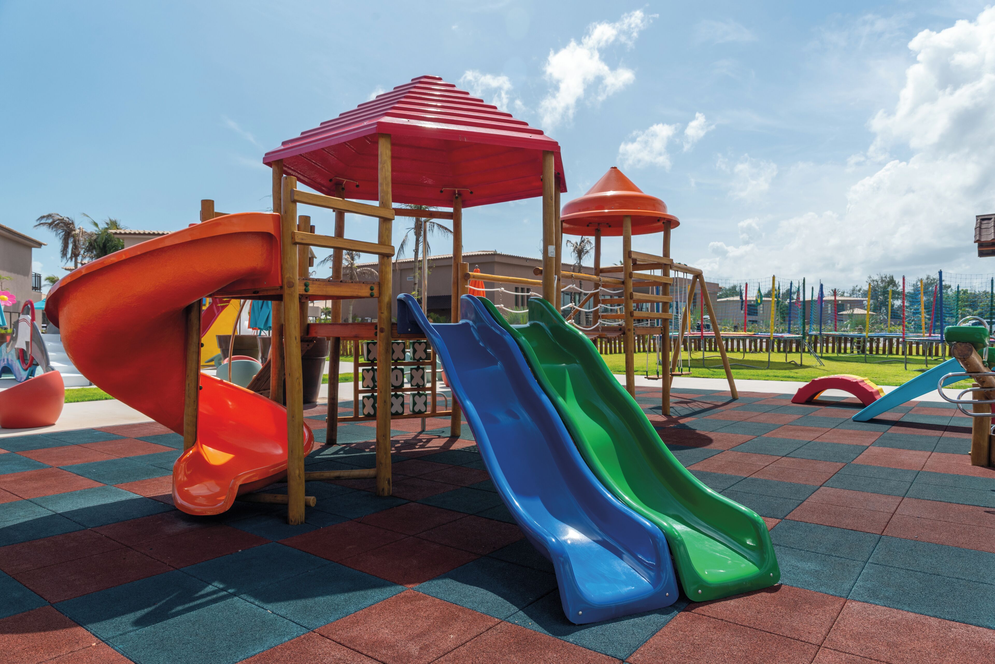 Un parque infantil con toboganes y una estructura de juegos de madera.