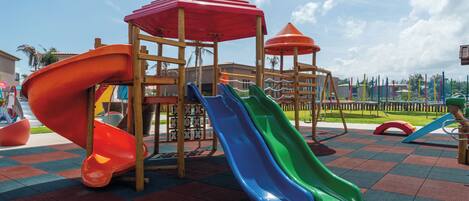 Un parque infantil con toboganes y una estructura de juegos de madera.