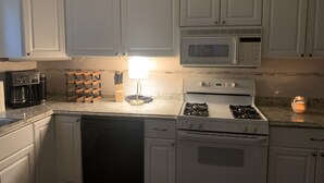 A kitchen with white cabinets, a microwave, a gas stove, a dishwasher, and a coffee maker. - Roomy Beachfront Apartment, Deck, Game Room! 2 Bedroom Apts by RedAwning (Norfolk)