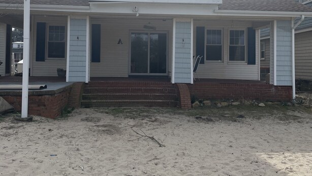 A two-story house with a balcony, a front porch, and a sandy driveway. - Roomy Beachfront Apartment, Deck, Game Room! 2 Bedroom Apts by RedAwning (Norfolk)