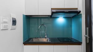 A compact kitchen with white cabinets, a stainless steel sink, and a black range hood.