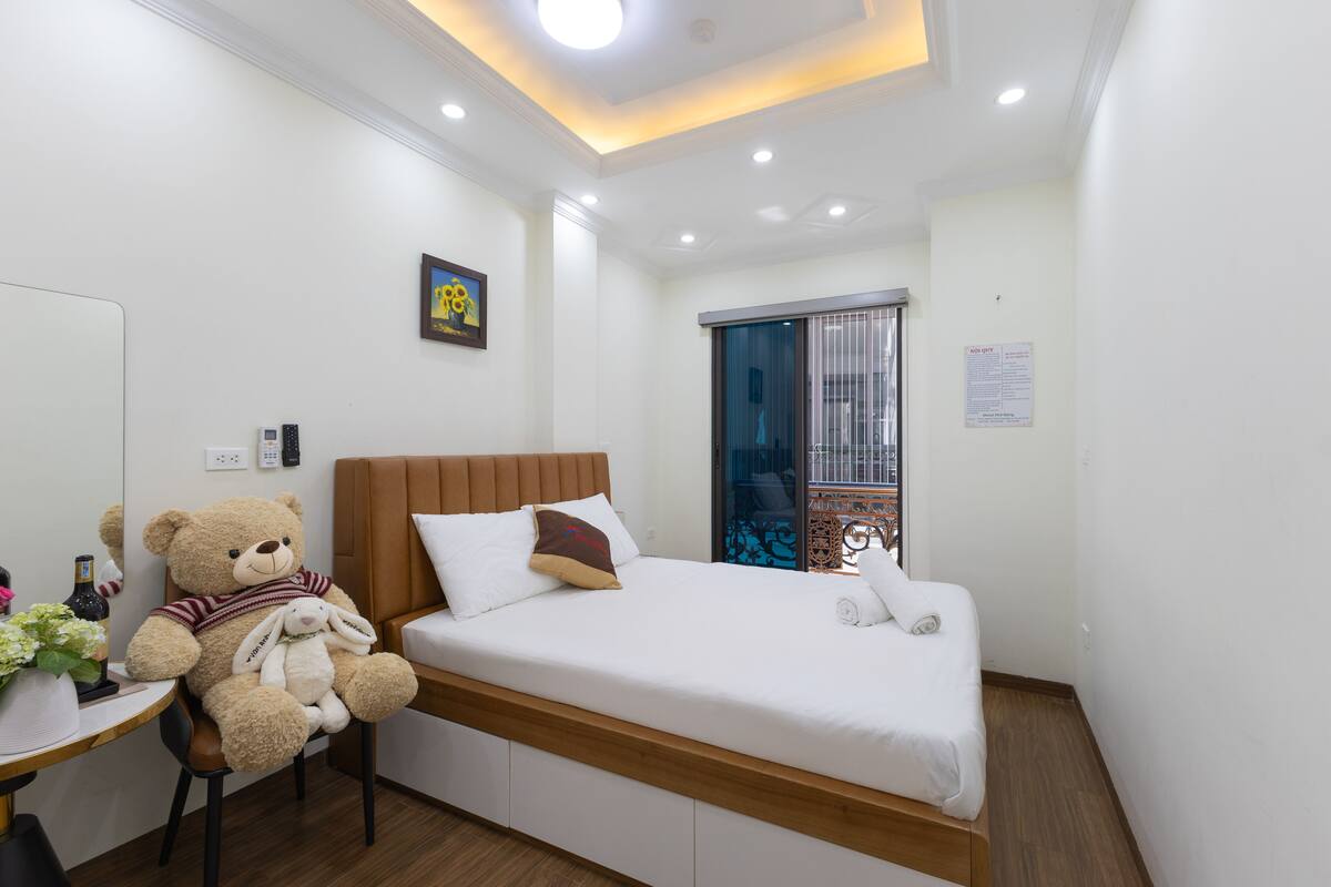 A modern hotel room with a bed, a desk, a chair, and a teddy bear.
