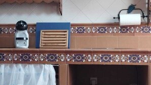 Una cocina con salpicadero de azulejos, un colgador para ollas y una planta en maceta sobre la encimera.