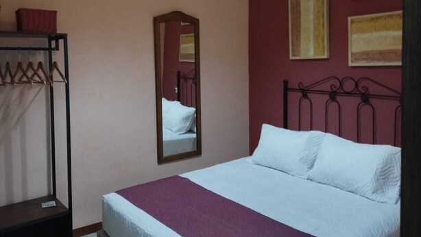 Un dormitorio con una cama individual, un armario colgado y dos cuadros enmarcados en la pared.