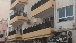 Un edificio de varios pisos con balcones, una farmacia y un restaurante llamado 'Pica Pica'.