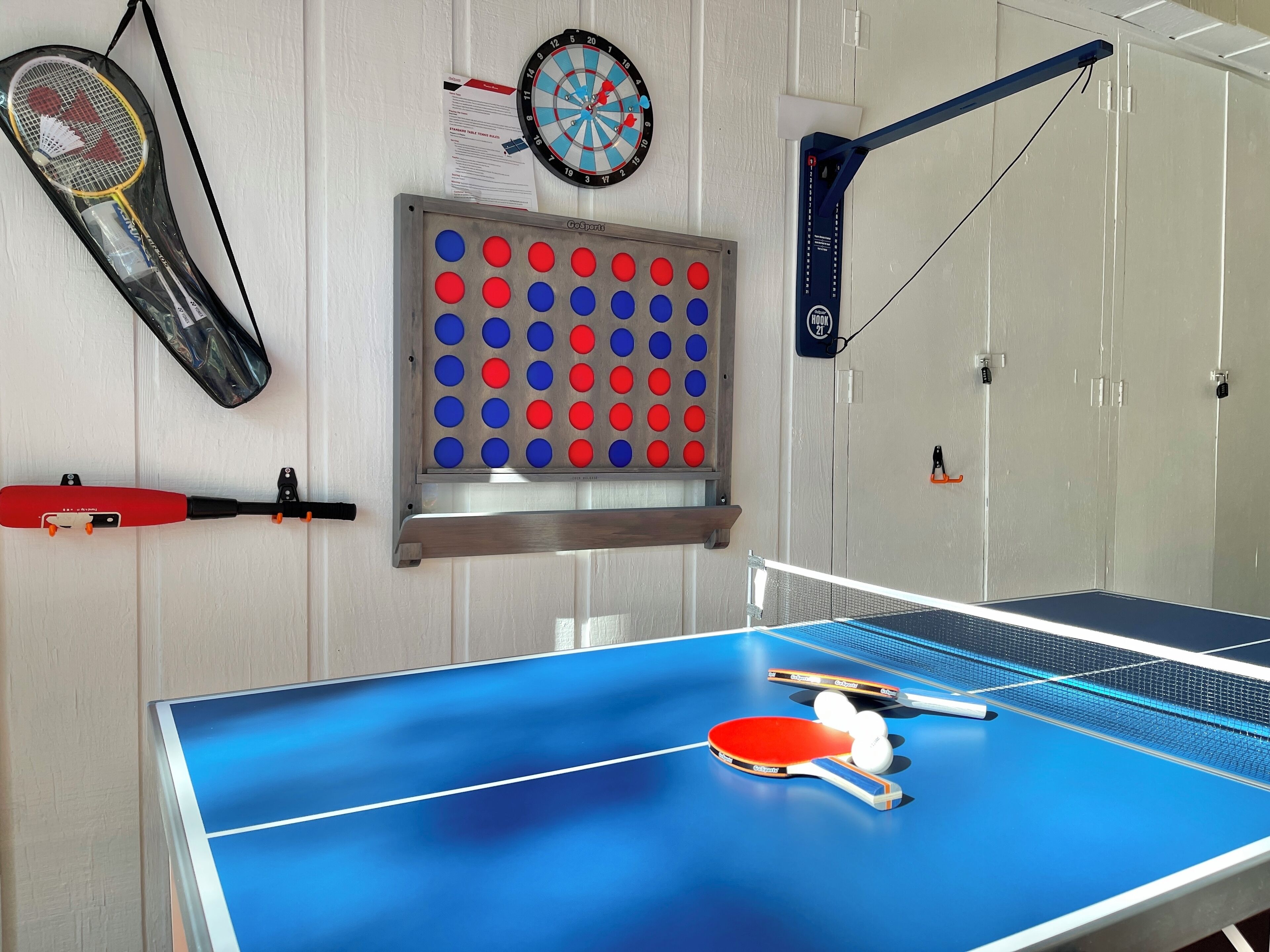 A ping pong table with paddles and balls, a dartboard, a badminton racket, and a Go board.