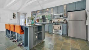 A modern kitchen with grey cabinets, stainless steel appliances, and a central island with bar stools.