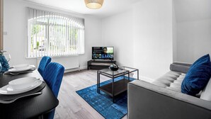 Un salon moderne comprenant un coin repas, un téléviseur et un canapé.