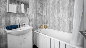 Une salle de bain avec un lavabo blanc, un miroir et une douche.