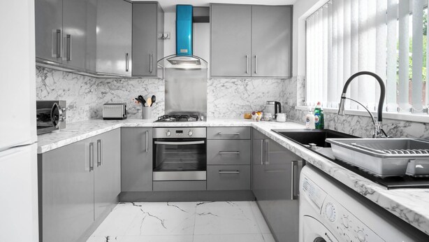 Une cuisine moderne avec des meubles de couleur grise, un four encastré, un four à micro-ondes et un évier.