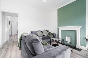 A living room with a grey sofa, a coffee table, and a fireplace. - 2 Bed House/families/contractors/free Parking (Birmingham)