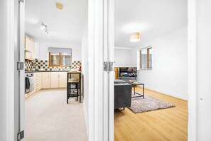 Eine moderne Küche mit Schachbrettmuster-Spritzschutz, Holzschränken und einem Essbereich mit grauem Sofa und Holzboden.