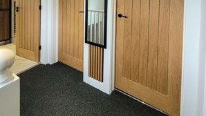 Un couloir avec trois portes en bois, un mur blanc et une moquette noire.