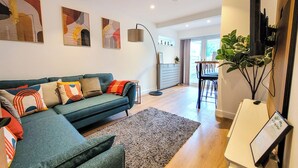 Un salon moderne avec un canapé de couleur turquoise, un petit tapis et des œuvres d’art abstraites accrochées au mur.