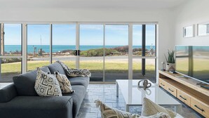 A modern living room with a large sliding glass door leading to a balcony with a view of the ocean. - Seascape at Boomer 2 Ocean Rd, Port Elliot (Port Elliot)
