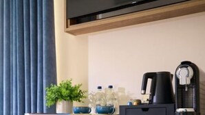 A hotel room with a desk, a chair, a television, and a coffee maker. - The James Hotel (Tralee)