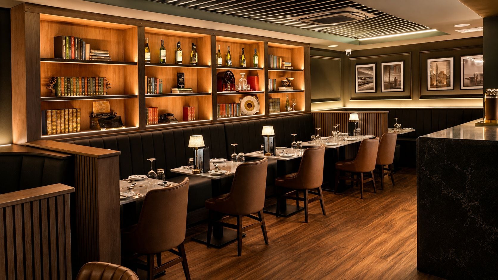 Een restaurant met houten boekenkasten, leren bankjes en een marmeren bar.