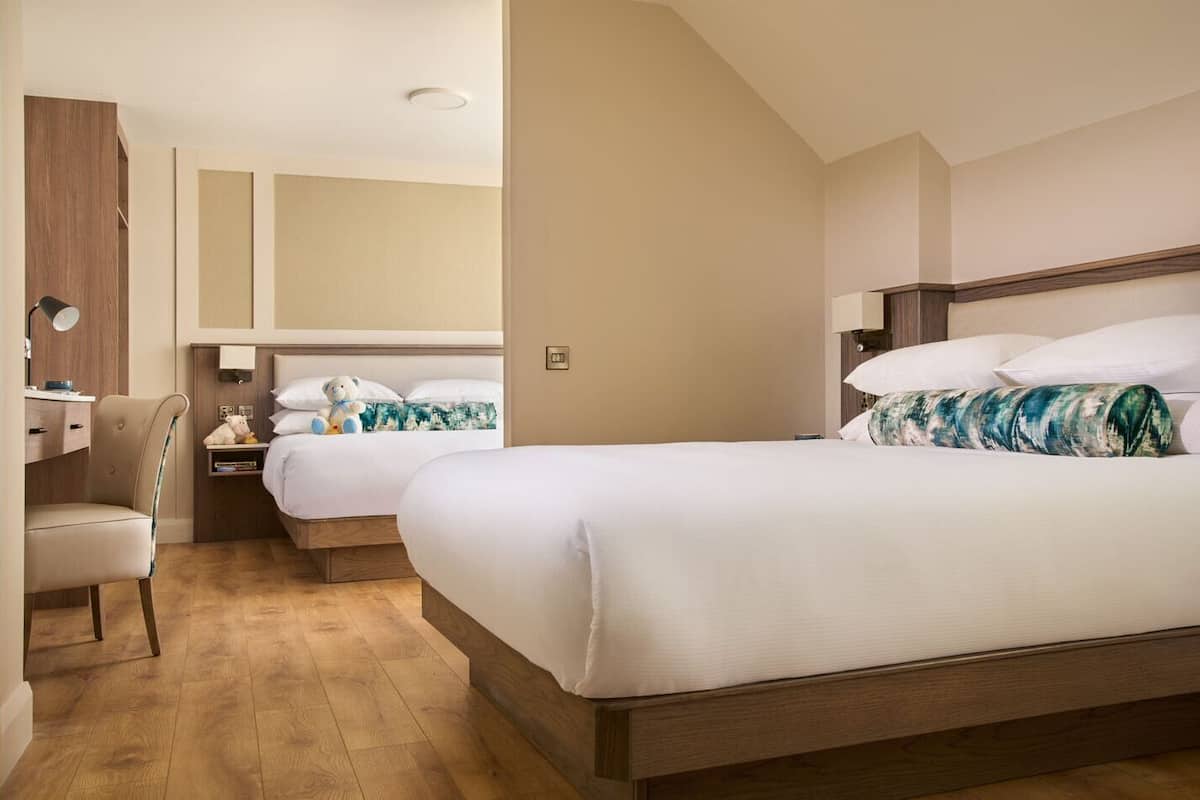 Une chambre d’hôtel avec deux lits, un bureau et une chaise.