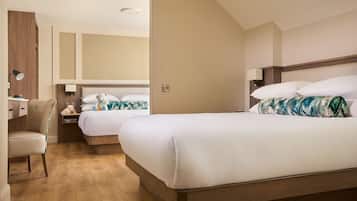 Quarto de hotel com duas camas, uma escrivaninha e uma cadeira.