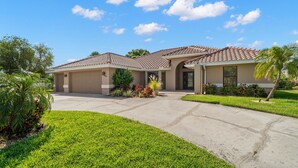 A residential house with a garage, a driveway, and a well-maintained lawn. - Surfside Beach House | Pvt Pool, Grill, Office (Apollo Beach)