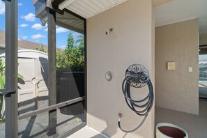 Une pièce dotée d’une porte coulissante, d’une caméra de surveillance fixée au mur, d’une prise de courant et d’un tuyau.