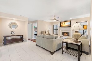 A living room with a sofa, a coffee table, a TV, and a fireplace.