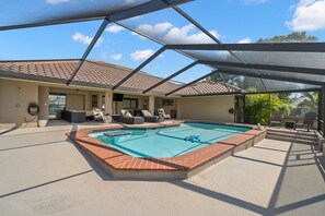 A covered outdoor swimming pool with a tiled deck, lounge chairs, and a pergola structure. - Surfside Beach House | Pvt Pool, Grill, Office (Apollo Beach)