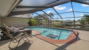 An indoor swimming pool with lounge chairs and a view of palm trees and houses. - Surfside Beach House | Pvt Pool, Grill, Office (Apollo Beach)