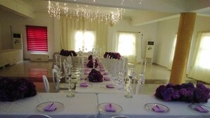 A banquet hall with long tables set for a formal event, featuring white chairs and purple table settings. - ROSES REGENCY HOTEL & SUITES (Abuja)