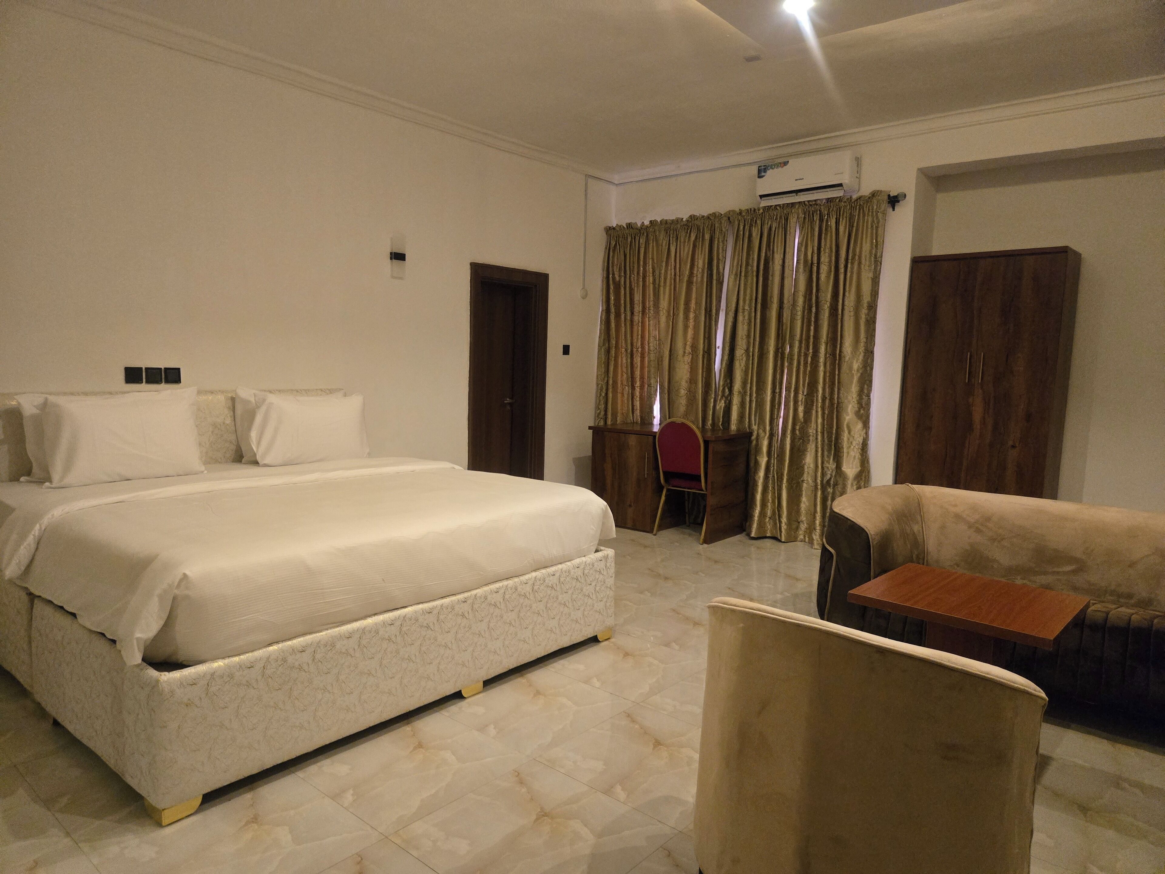 Une chambre d’hôtel avec un grand lit, un bureau, une chaise et un canapé.