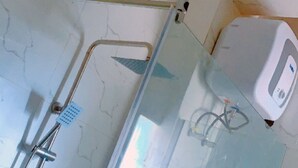 A bathroom with a glass shower enclosure, a handheld showerhead, and a wall-mounted faucet. - ROSES REGENCY HOTEL & SUITES (Abuja)