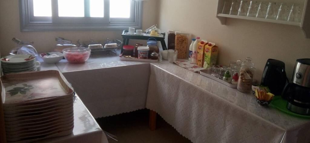 A kitchen area with a table set for a meal, various food items, and kitchen appliances.