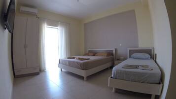 A hotel room with two beds, a wardrobe, and a TV.
