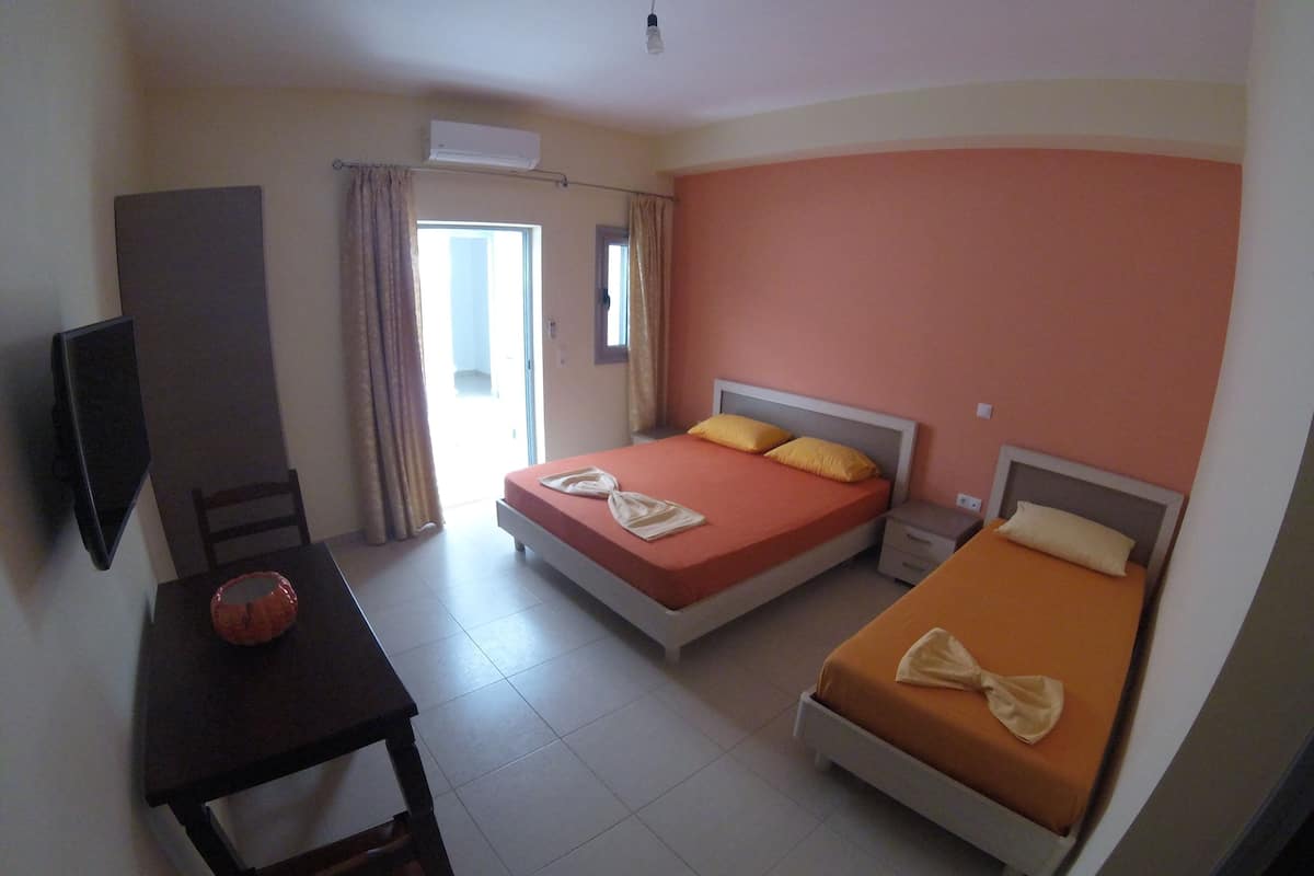 Habitación de hotel con dos camas, televisión, mesa y una silla.