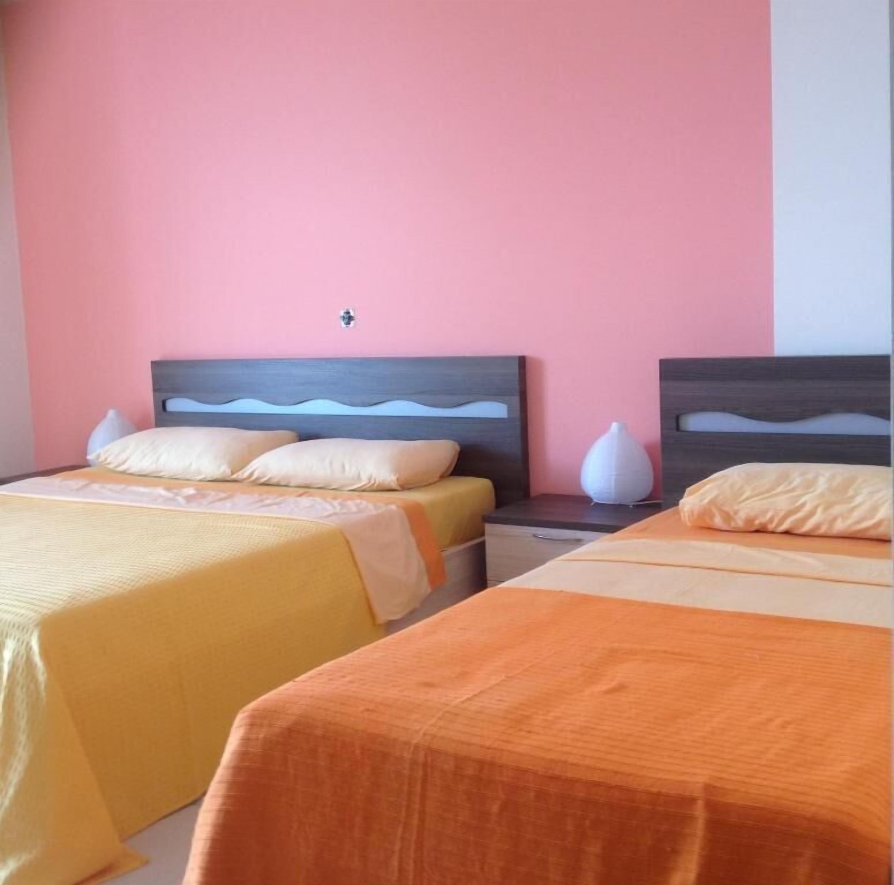 Habitación de hotel con dos camas, cada una con cabecero de madera y almohadas blancas.