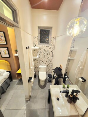 A compact bathroom with a toilet, sink, and shower area. - Somos Hotel - San Juan (San Juan)