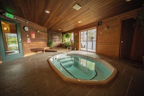 Piscina interna com paredes de madeira e um banco.