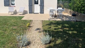 Una casa con patio empedrado, sendero de grava y mobiliario exterior.