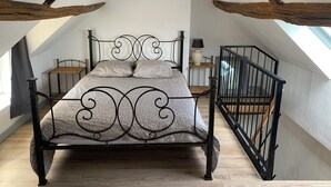 Un dormitorio tipo loft con estructura de cama metálica, suelo de madera y tragaluz.
