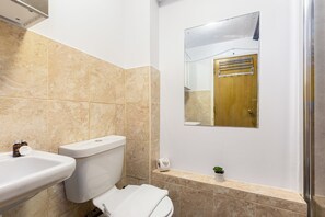 Un baño con inodoro, lavamanos y una pequeña planta en maceta.