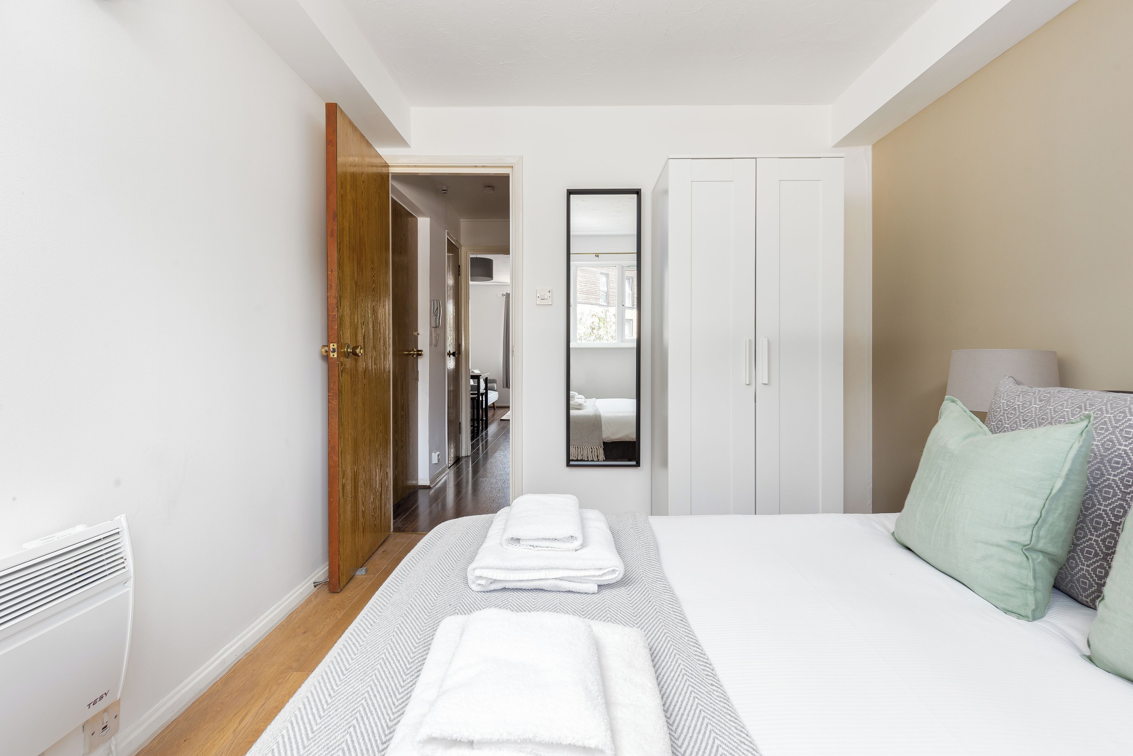 Ein Schlafzimmer mit Bett, Kleiderschrank und Spiegel.