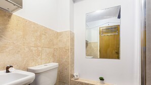 A bathroom with a toilet, sink, and a small potted plant. - The Bridge Flats (London)