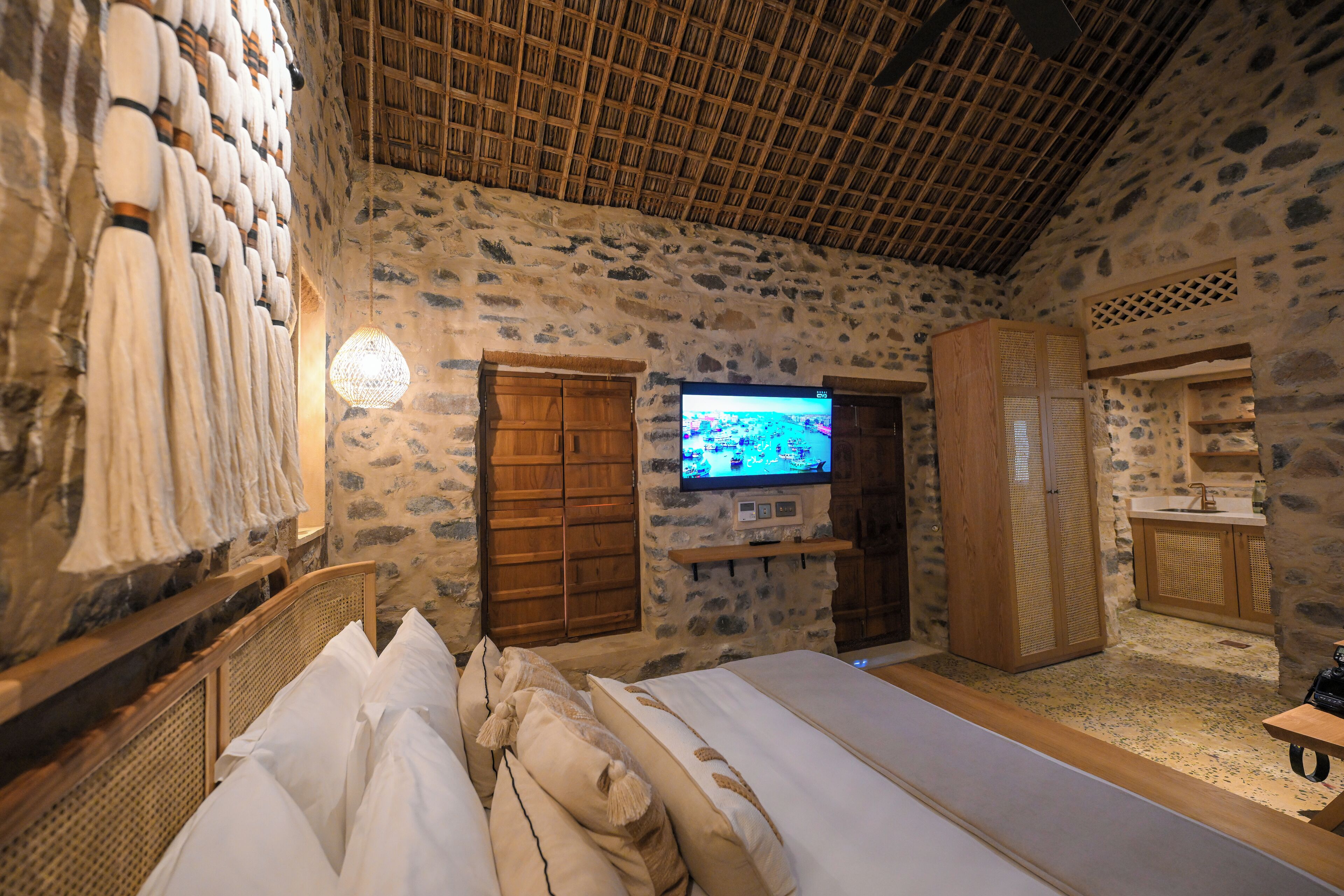 Ein Zimmer mit Stehwänden, einem Bett, einem Fernseher und einem Holzschrank.