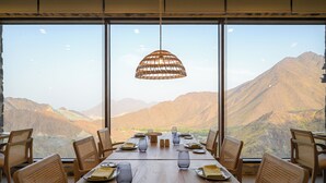 Ein Esstisch für sechs Personen mit Blick auf Berge durch große Fenster.