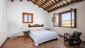 Une chambre à coucher avec un lit, une chaise, une table de chevet, une fenêtre et un plafond en bois.