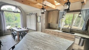 A spacious kitchen with a large island, wooden ceiling beams, and a view of the outdoors. - WATERFRONT NEWER HOME WITH A DOCK.  4 BEDROOM 2 BATH.   (Sebago)