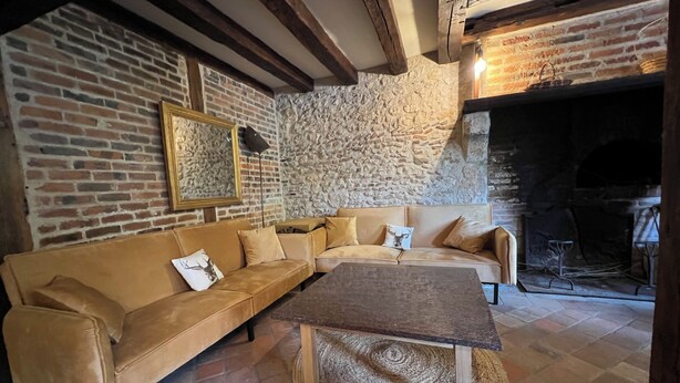 Ein gemütliches Wohnzimmer mit einer Ledersofa, einem Holztisch und einer Steinwand.
