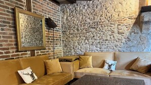 Ein gemütliches Wohnzimmer mit Backsteinwand, einem großen Spiegel im Bilderrahmen und zwei Sofas mit passenden Kissen.